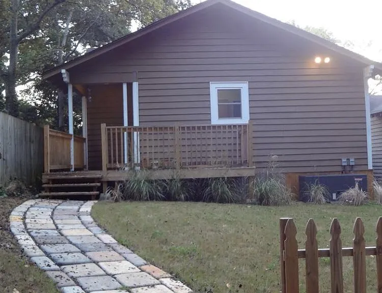 Backyard and large rear parking area with stone walk way leading to back porch and back door.