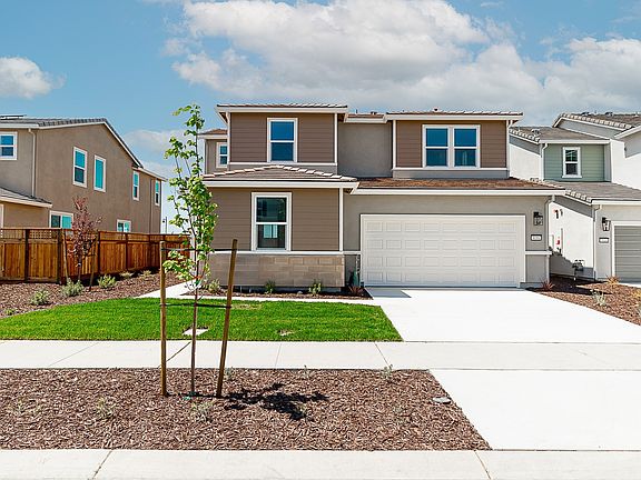 A modern two-story residential home with a well-maintained lawn, surrounded by other similar houses