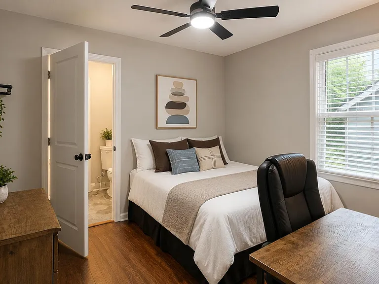 Furnished bedroom with a full bed, desk workspace, ceiling fan, and window blinds, with convenient access to a nearby bath.