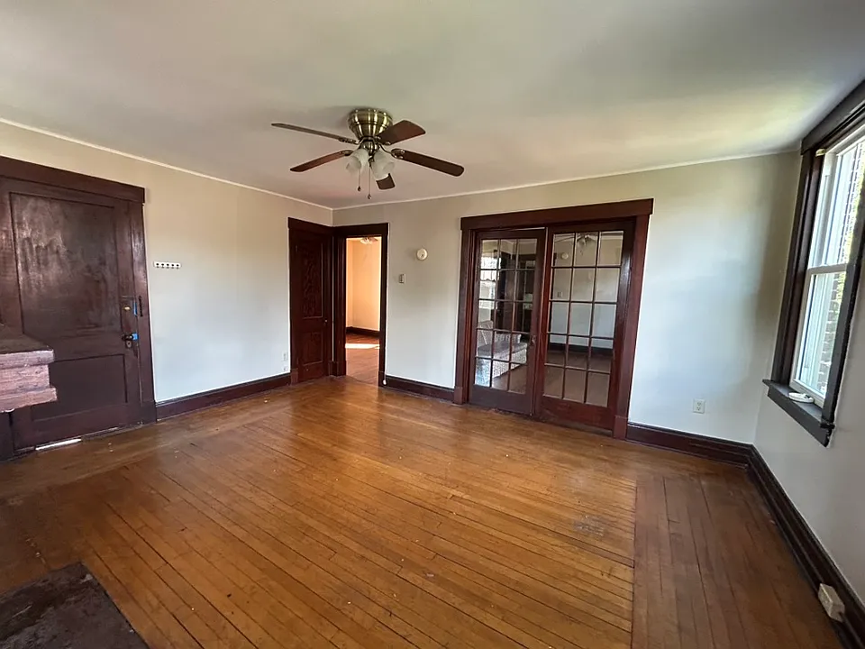 View from porch door into full living room. Dining room beyond glass doors, to left, entry closet and bedroom one.
