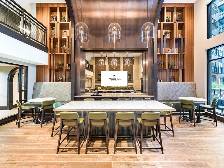 Community demonstration kitchen with a marble island, bar seating, and arched wood detailing designed for hosting, shared meals, and everyday connection.