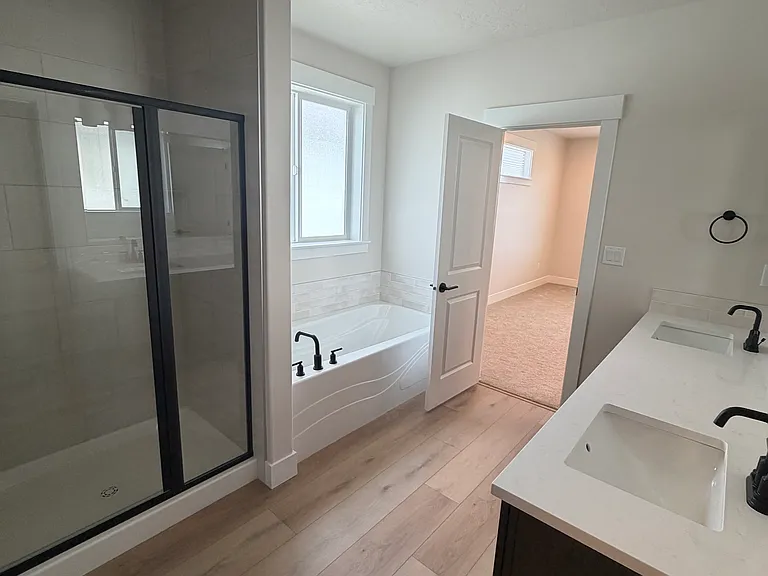 Enjoy spa-like living in the expansive primary bathroom, complete with dual vanities, a large walk-in closet, a separate glass-enclosed shower, and a deep soaking tub.