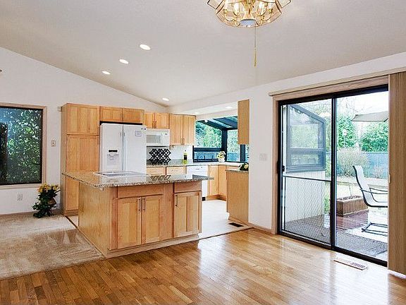 The large, granite, cook-top island, with Jenn-Aire range and oven, and hardwood floor accentuate the spacious eating area off of the kitchen. The currently open Hunter-Douglas cellular slider blinds provide additional insulation against those cold, winter days.