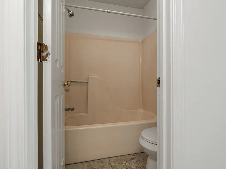Tub/shower combo in the full bathroom with tile flooring