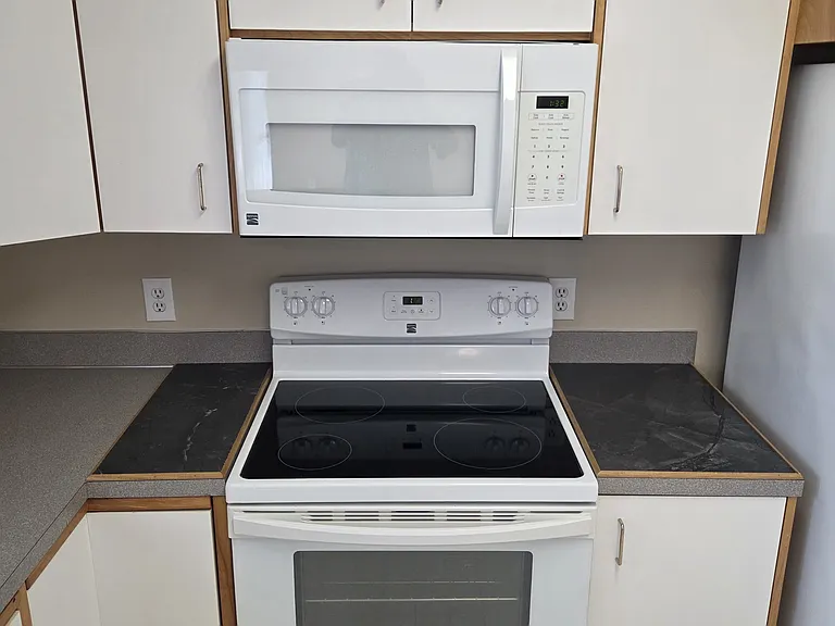 View of the range, adjacent built-in porcelain hot pot trivets, and microwave oven.