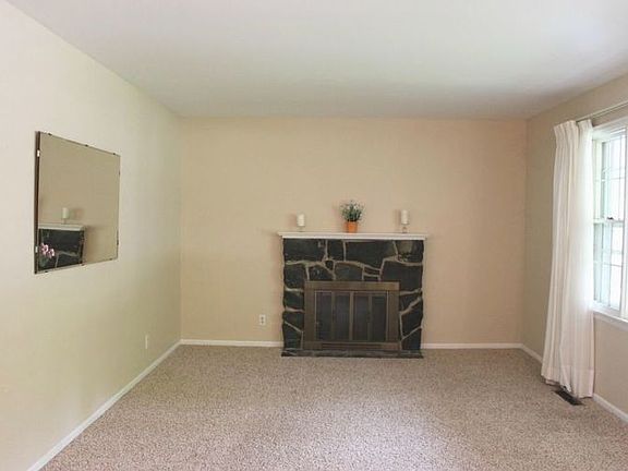 The living room features a wood burning fireplace and picture window.