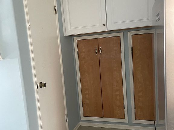 Additional cabinets in kitchen and closet or pantry space behind wooden doors. Door on left leads to bathroom