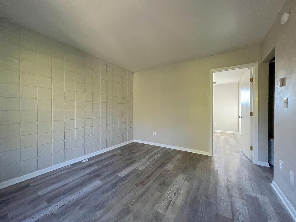 The open-concept living area features fresh paint, luxury vinyl plank flooring, and a door leading to the apartment's private entrance.