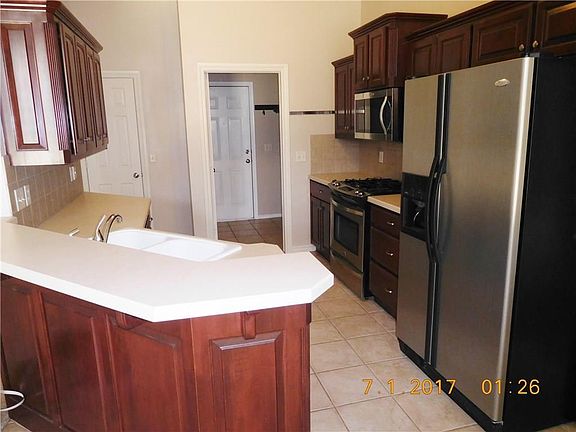 Side-by-side refrigerator remains, stainless appliances. Convenient breakfast bar and walk-in pantry.