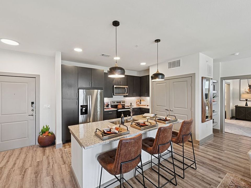 Kitchen with espresso cabinetry, speckled granite countertops, white subway tile backsplash, stainless steel appliances, and hard surface flooring