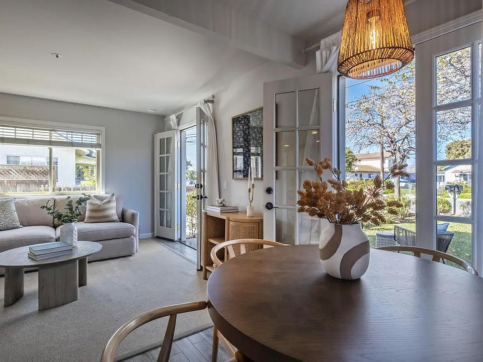 Open concept living room and dining area with double french doors that open up to the landscaped front yard.