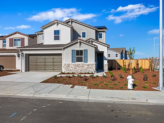 A two-story residential house with a garage, surrounded by a landscaped yard and set against a clear