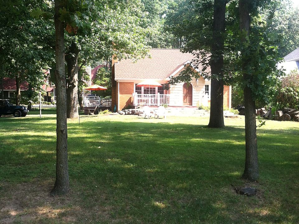 large grassy front yard with a fire pit.