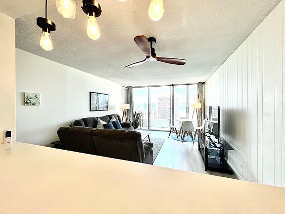 Living Room. 2 Reclining sofas, coffee table, 58" Smart TV w/ stand, ceiling fan (view from kitchen counter)