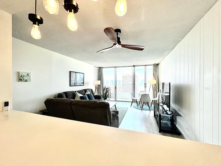 Living Room. 2 Reclining sofas, coffee table, 58" Smart TV w/ stand, ceiling fan (view from kitchen counter)