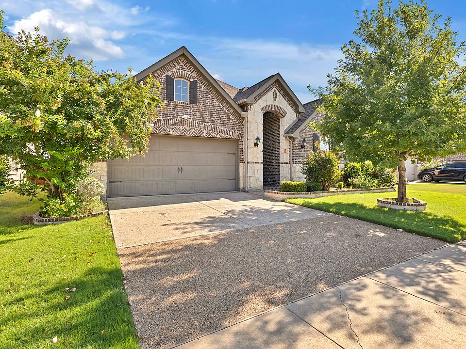 Traditional home featuring brick and stone siding, concrete driveway, a 2-car garage, and a front lawn