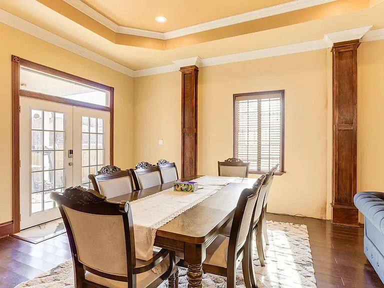 Formal dining area with a large table, detailed millwork, and French doors providing easy access to the backyard patio.