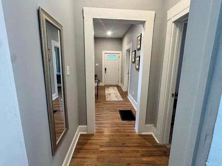 Welcoming entry hallway with wood-look floors, tall trim, and easy access to adjacent rooms for convenient flow.