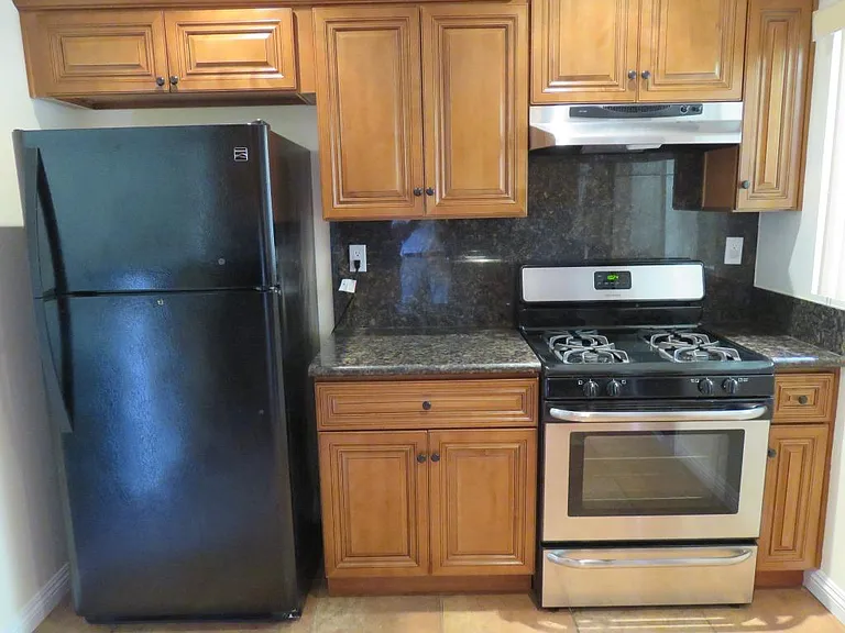 Kitchen stove / oven, fridge and storage cabinets.