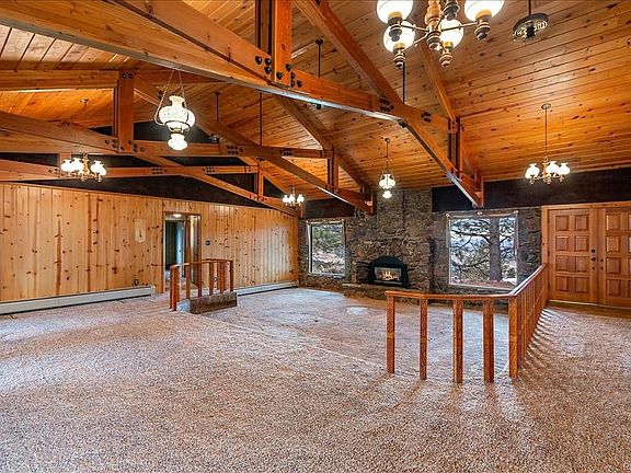 Sunken Living Room with natural rock fireplace, exposed beams, tongue groove ceiling, large windows, double front door.