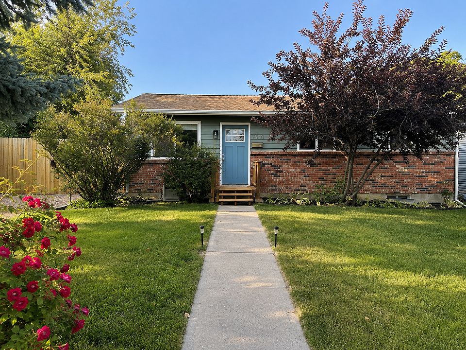 Front entrance with two large lilac bushes, roses and lilies.