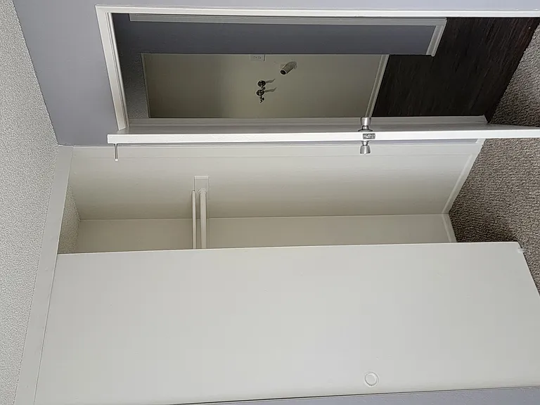 Carpeted bedroom and hallway nook with washer/dryer hookups at Grand Oaks Apartments in Lake Elsinore, California.
