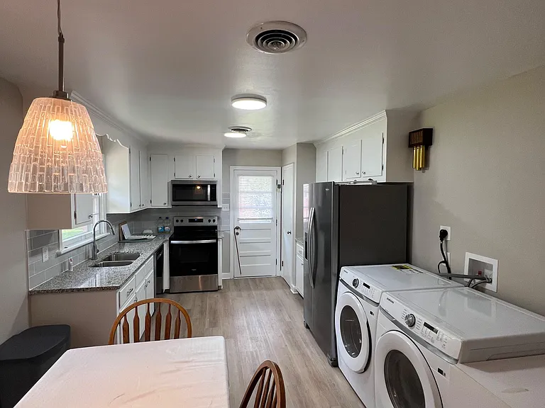 Galley-style kitchen with ample cabinet storage, granite-look counters, and a full appliance suite with adjacent laundry.