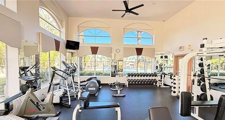 Spacious fitness room with cardio machines, free weights, and strength stations, plus large windows for natural light.