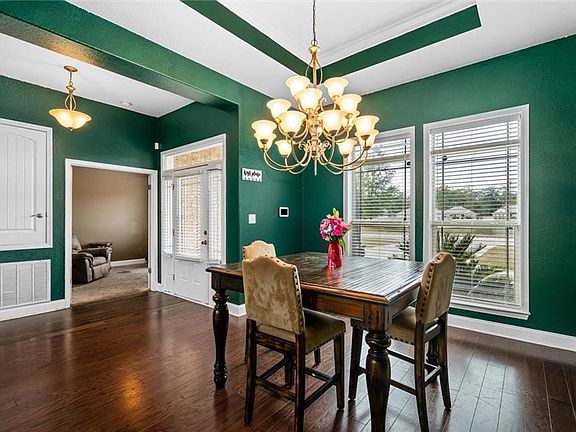 Dining area with crown molding, plenty of natural light, dark wood-type flooring, and a notable chandelier