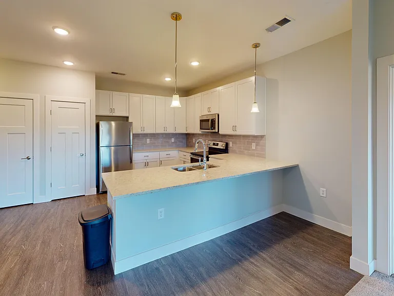 The Dogwood floor plan is an open-concept layout, featuring a large kitchen with wood-style flooring, a breakfast bar, pendant lighting, and a pantry. The Dogwood floor plan is an open-concept layout, featuring a large kitchen with wood-style flooring, a 