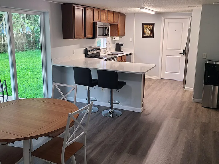 Eat-in kitchen with quartz peninsula seating, stainless appliances, and sliding doors opening to the backyard patio.