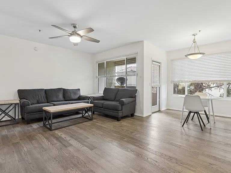 Large great room with new fan, new wood flooring, new windows, like new blinds, sofa and love seat and small table and chairs