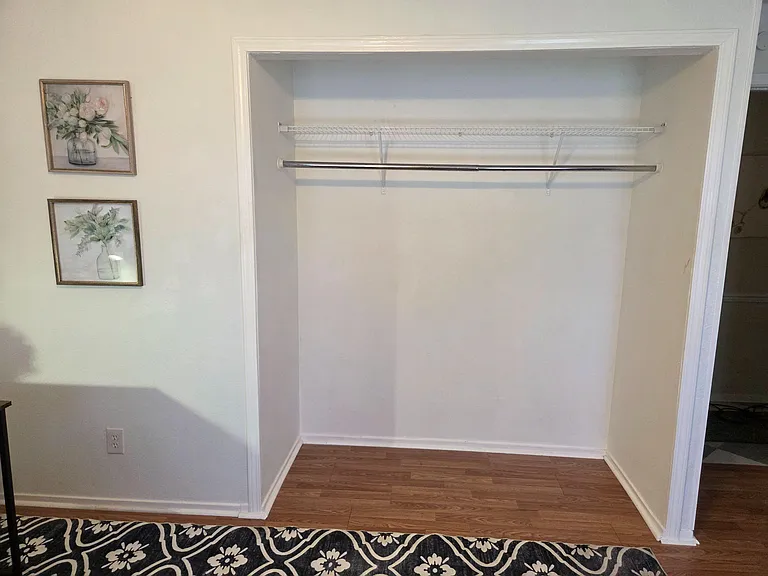 Spacious walk-in closet with a long hanging rod and upper wire shelf for easy organization and extra storage.