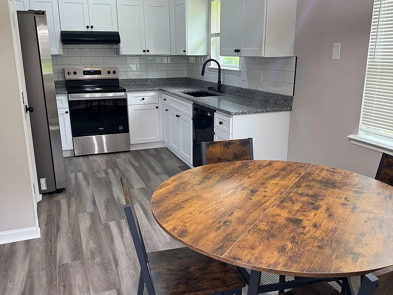 Eat-in kitchen with white shaker cabinets, ample counter space, stainless appliances, and a nearby dining table.