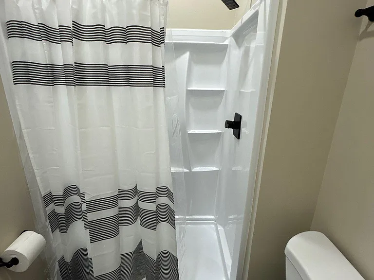 Compact full bath with a tub/shower combo, built-in shelving, and matte-black fixtures for everyday convenience.
