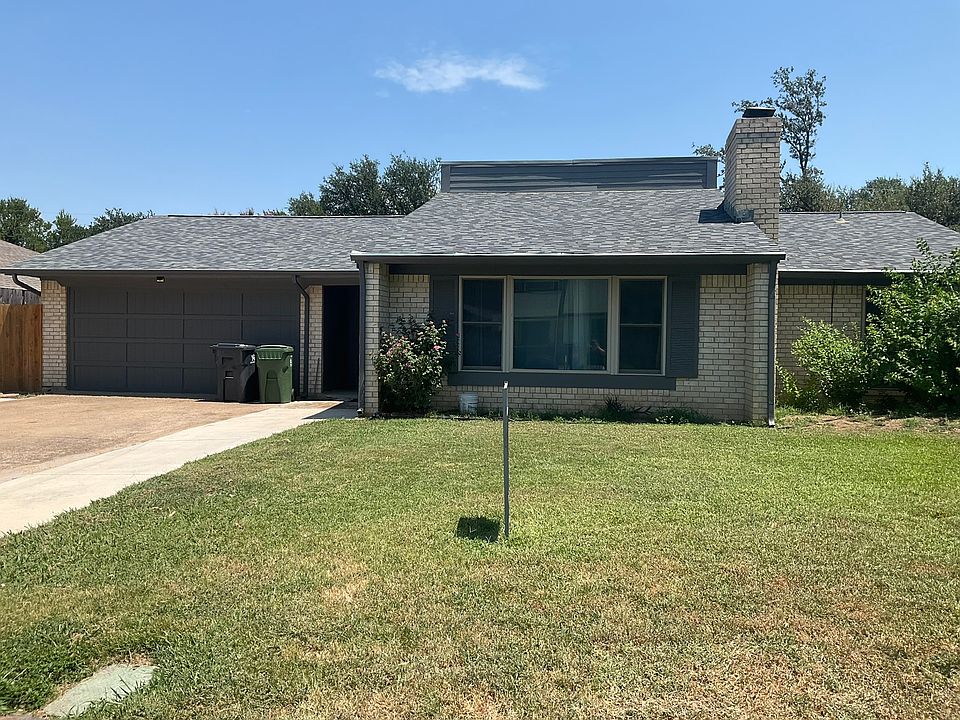 View of front of home with concrete driveway, a front lawn, a shingled roof, and brick siding