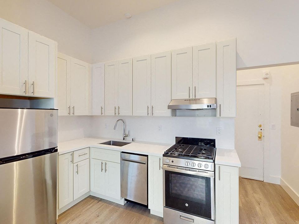 Kitchen with multiple cabinets, refrigerator, stove, range hood, and sink