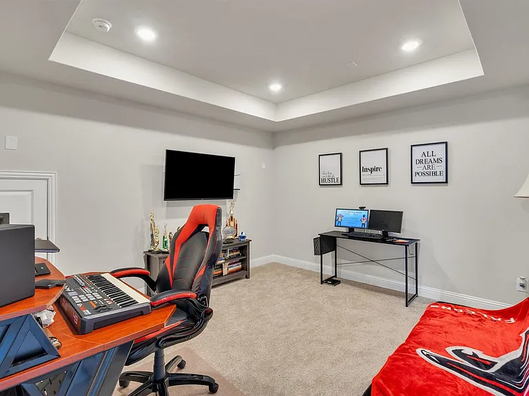 Recessed lighting illuminates a tray ceiling and light-colored carpeting