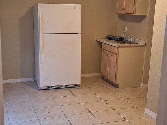 Kitchenette with refrigerator, sink, 2 burner countertop stove, and storage.