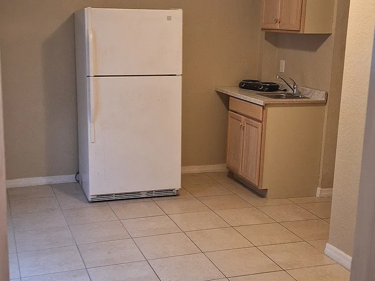Kitchenette with refrigerator, sink, 2 burner countertop stove, and storage.