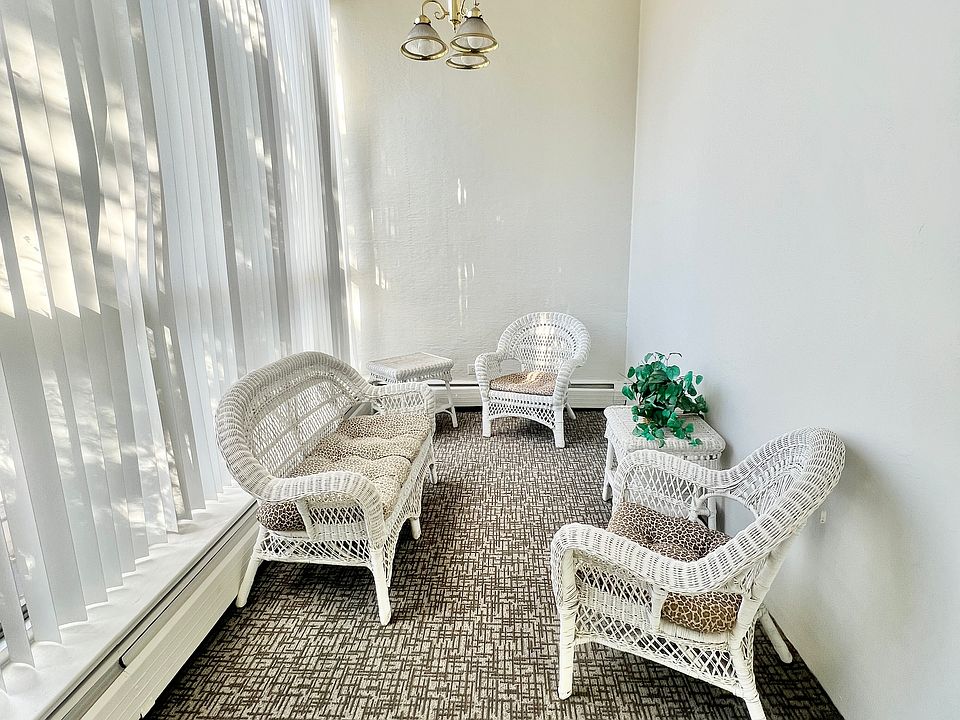 Charming sunroom with white wicker furniture and soft carpeting, basking in natural light.
