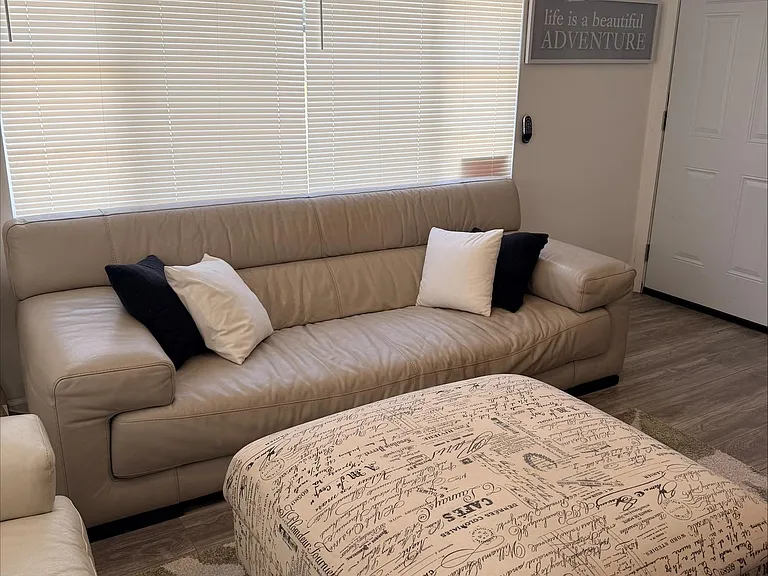 Inviting living area with a comfortable sofa, oversized window with blinds, and a spacious layout for relaxing or entertainin