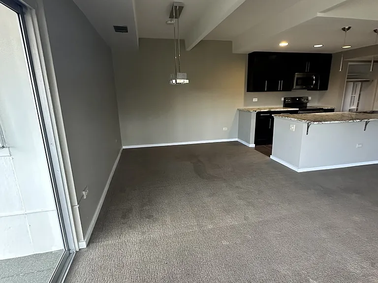 View from inside corner of balcony sliding doors toward the dining area and kitchen peninsula