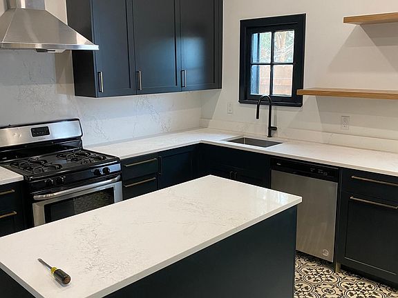 New cabinets, kitchen island, appliances, tile, and shelving. Notice the lighted range hood and fan