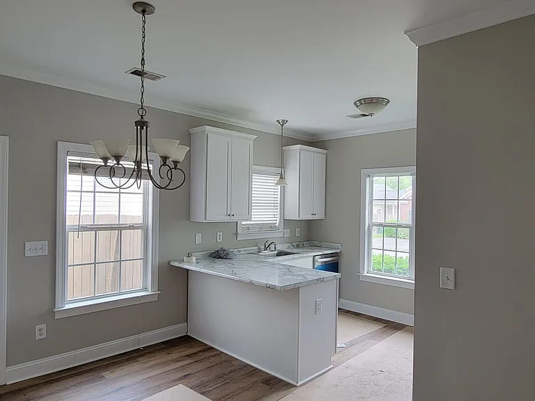 Dining area and kitchen. New countertop with bar seating. New LVP flooring, new 42" tall cabinets with soft-close doors and drawers. Side entry door to patio.