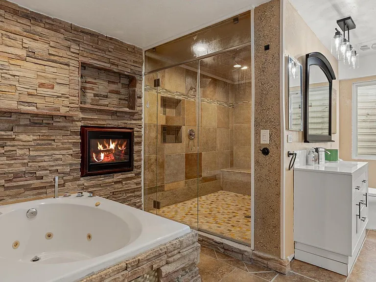 Spa-style bath with a jetted soaking tub, walk-in glass shower with tile surround, and a wide vanity with storage.