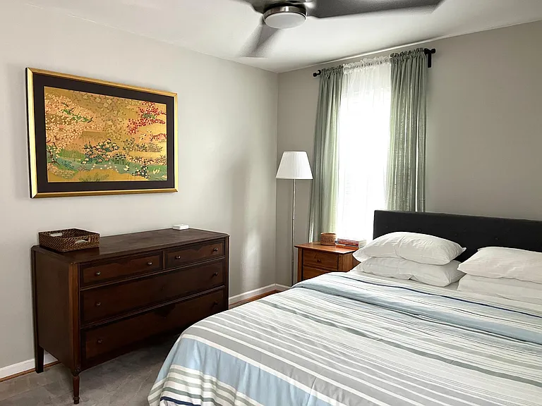 Bedroom #one with dresser, bed, side table and modern, quiet ceiling fan.