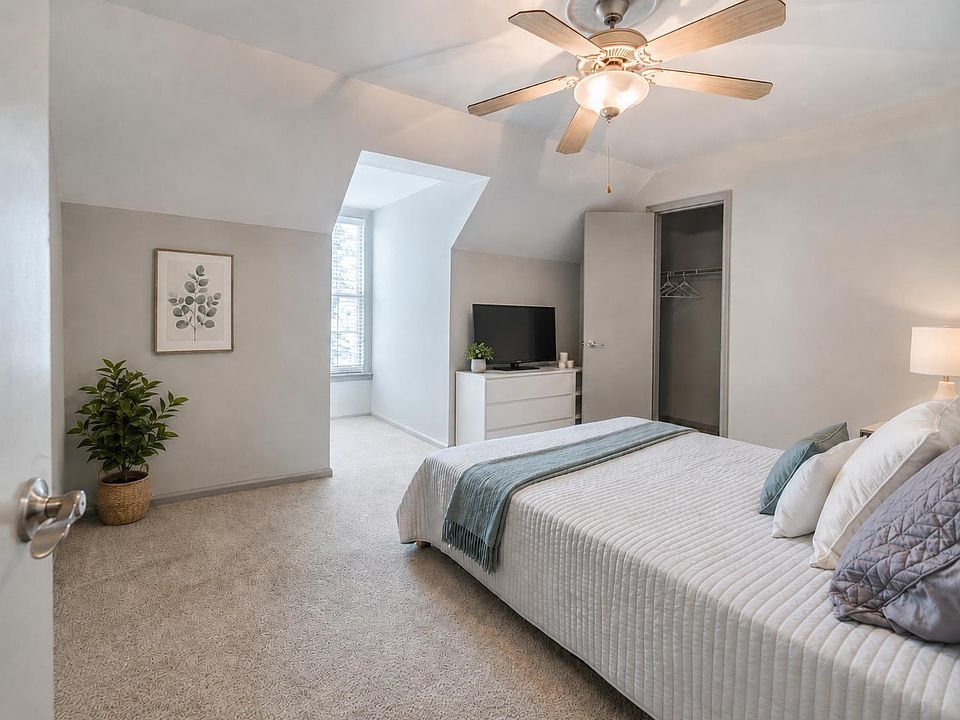 Spacious bedroom with a ceiling fan, carpeted floors, and an alcove window nook plus closet storage.