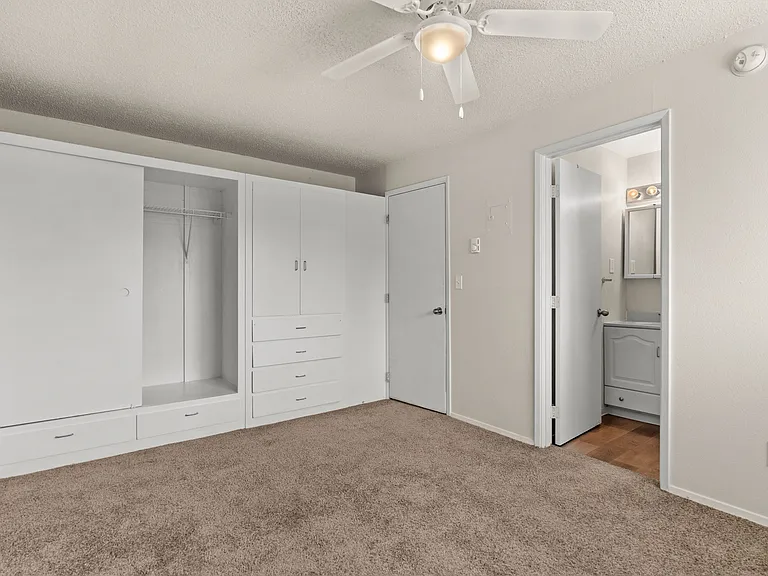 Cozy bedroom featuring generous built-in storage, soft carpeting, and direct access to the bathroom. Cozy bedroom featuring generous built-in storage, soft carpeting, and direct access to the bathroom.