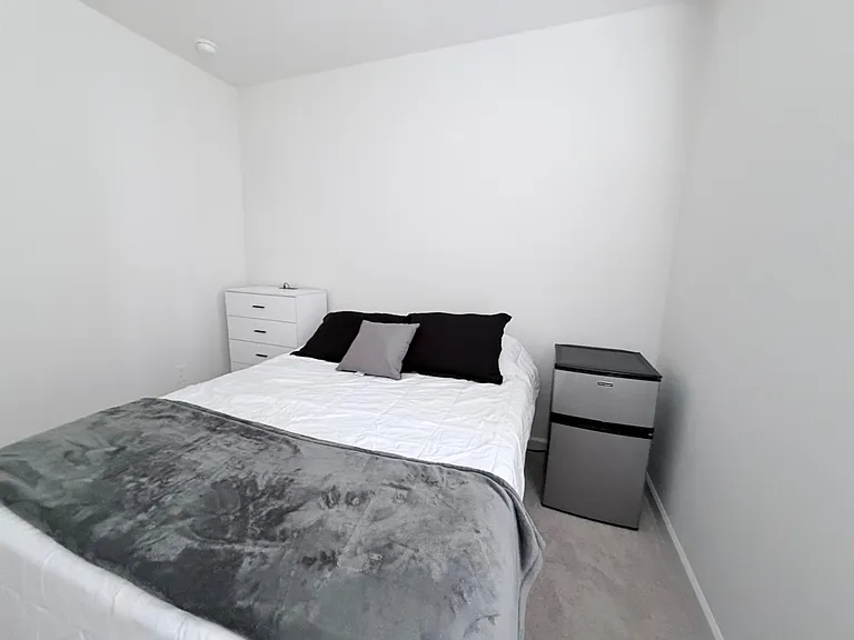 Private bedroom with a full bed, dresser storage, and an in-room mini fridge for added convenience.